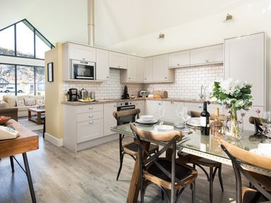 A kitchen with white cabinets and a dining table set with plates and wine bottles at Lambs Lodge in Bamburgh