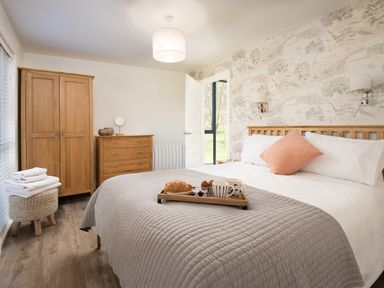 A bedroom with a wooden bed chest of drawers and wardrobe at Lambs Lodge in Bamburgh