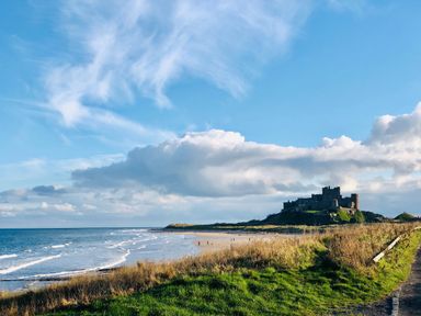 A coastal landscape with a castle on a hill near the beach at Lambs Lodge in Bamburgh