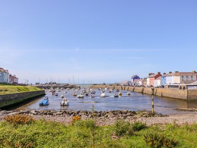 A harbor with boats on the water surrounded by houses and greenery at Bari in Aberaeron