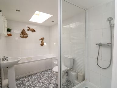 A bathroom with a bathtub sink toilet shower and decorative wall hangings at Bari in Aberaeron