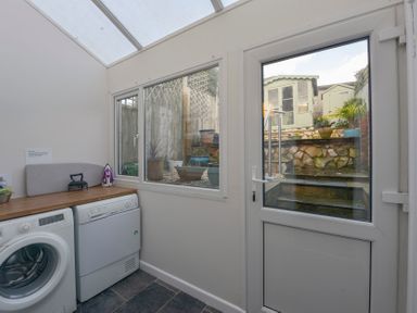 A utility room with a washing machine dryer countertop window and door leading outside at Meadow View Cottage in Lympstone