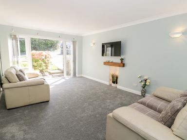 A living room with two sofas a wall-mounted TV and a window looking outside at Clyd Fan in Harlech