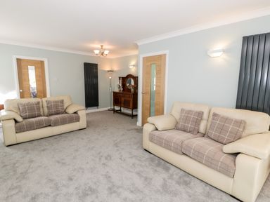 A living room with two beige sofas and a wooden sideboard at Clyd Fan in Harlech