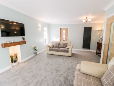 A living room with two sofas a wall mounted television and a wooden table at Clyd Fan in Harlech