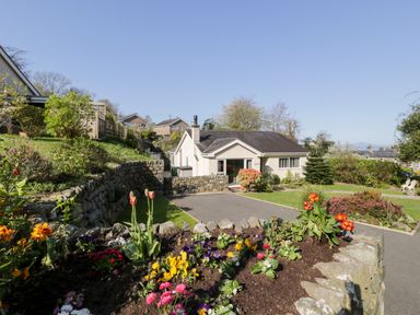 A house with a garden and flower beds surrounded by stone walls at Clyd Fan in Harlech