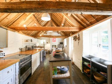 A kitchen with wooden beams and a black countertop island at The Old Post Office in Coln St Aldwyns