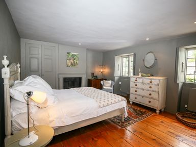 A bedroom with a bed a dresser a chair and a fireplace at The Old Post Office in Coln St Aldwyns