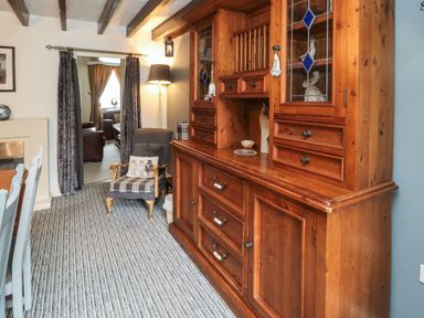 A dining room with a wooden dresser chair and a floor lamp at Victoria Cottage in Amble