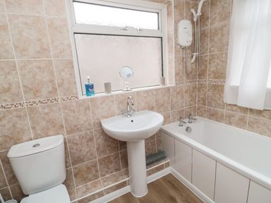 A bathroom with a toilet sink and bathtub with shower at Victoria Cottage in Amble