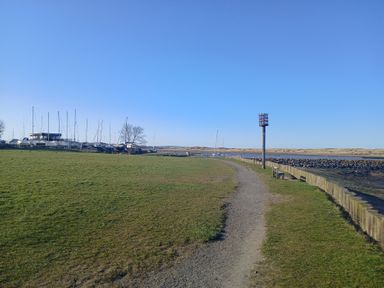 A gravel path along a grassy area with benches and boats docked near water at Victoria Cottage in Amble