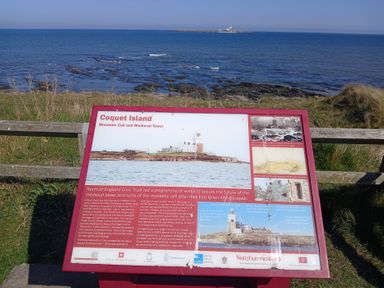 An information board about Coquet Island with the sea and the island in the background at Victoria Cottage in Amble