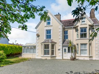A residential building with bay windows and a gravel driveway at Bryn Rhosyn in Nefyn