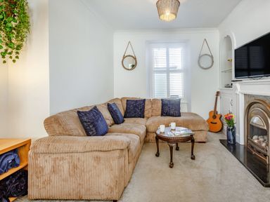 A living room with a sectional sofa and coffee table near a window and fireplace at Bryn Rhosyn in Nefyn