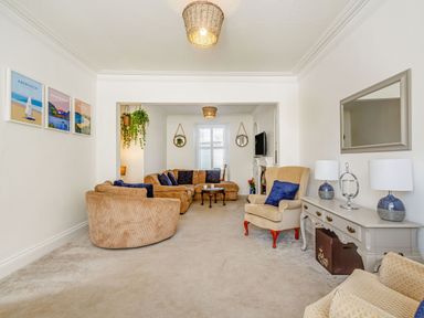 A living room with sofas armchairs a coffee table wall art and a sideboard with lamps at Bryn Rhosyn in Nefyn