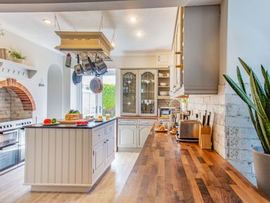 A kitchen with wooden countertops and hanging pots above an island at Bryn Rhosyn in Nefyn