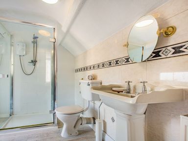 A bathroom with a shower enclosure toilet and sink with mirror at Bryn Rhosyn in Nefyn