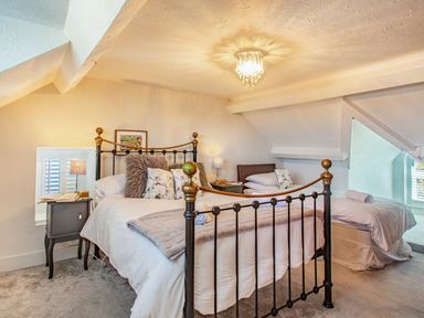 A bedroom with a metal bed frame bedside tables and a single bed at Bryn Rhosyn in Nefyn