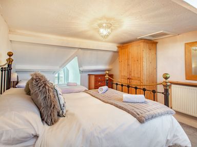A bedroom with two beds a wooden wardrobe a wooden chest of drawers and a mirror at Bryn Rhosyn in Nefyn