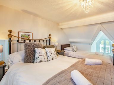 A bedroom with two beds with pillows and blankets a bedside table and a window at Bryn Rhosyn in Nefyn