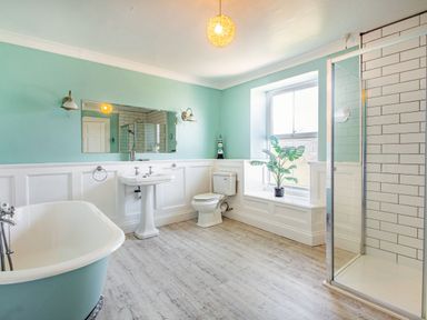 A bathroom with a bathtub sink toilet shower and a plant on a window ledge at Bryn Rhosyn in Nefyn
