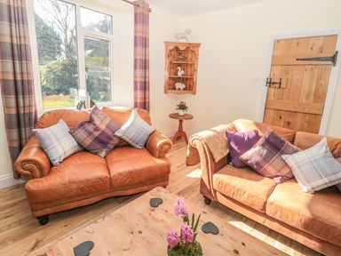 A living room with two leather sofas and a wooden door at Baytree in Alnwick