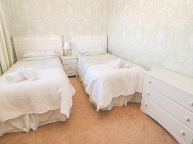 A bedroom with two single beds a bedside table with a lamp and a chest of drawers at Baytree in Alnwick