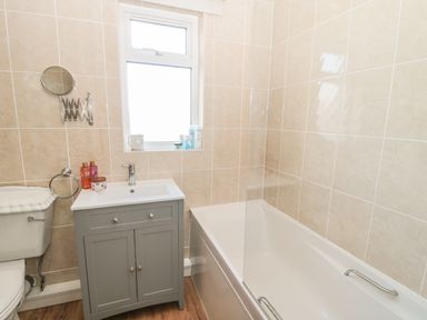 A bathroom with a toilet sink cabinet and bathtub with tiled walls at Baytree in Alnwick