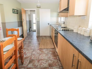 A kitchen with wooden cabinets a dining table with chairs and kitchen utensils on the counter at Baytree in Alnwick