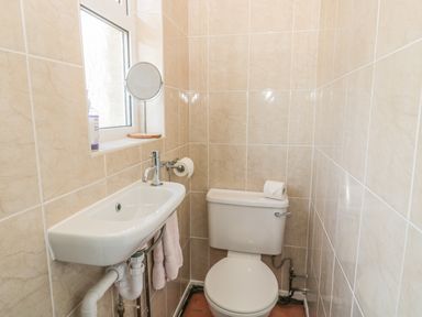 A small bathroom with a white toilet and a white sink under a window at Baytree in Alnwick