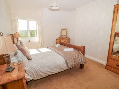A bedroom with a double bed bedside tables lamps a dressing table and a mirrored wardrobe at Appletree Alnwick