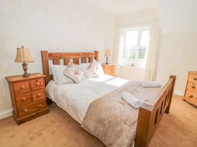 A bedroom with a wooden bed and nightstands with lamps at Appletree in Alnwick