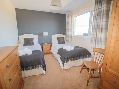 A bedroom with two single beds bedside table lamp wooden dresser wardrobe and chair at Appletree in Alnwick