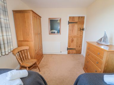 A bedroom with wooden wardrobe chair dresser with sailboat decoration and a wooden door at Appletree in Alnwick
