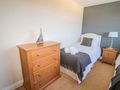 A bedroom with two single beds a wooden chest of drawers and a bedside table with a lamp at Appletree in Alnwick