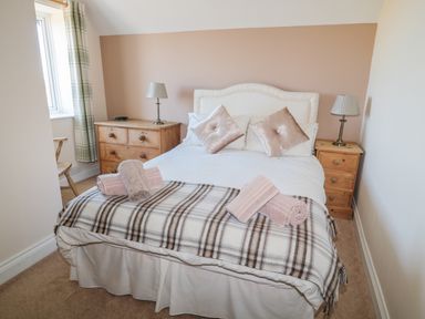 A bedroom with a double bed and pillows two wooden bedside tables with lamps and a dresser with drawers at Appletree in Alnwick
