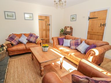 A living room with brown leather sofas and a wooden coffee table at Appletree in Alnwick