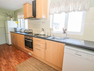 A kitchen with wooden cabinets a refrigerator microwave toaster sink and dishwasher at Appletree in Alnwick