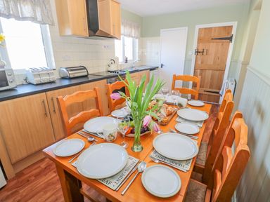 A kitchen with a wooden dining table set with plates glasses and tulips at Appletree in Alnwick