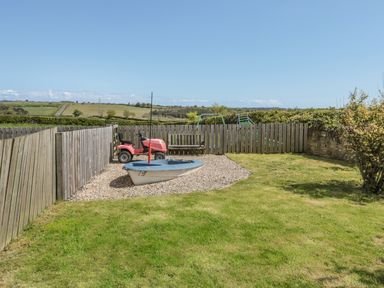 A backyard with a lawn mower bench and a small boat on gravel at Appletree in Alnwick