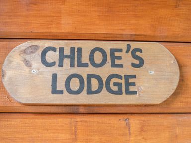 A wooden sign with Chloe's Lodge written on it mounted on wooden wall at Chloe's Lodge in Middleton Ryedale