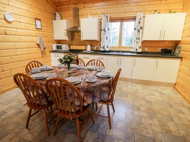 A kitchen with a dining table set with plates cups and glasses and wooden chairs at Chloes Lodge in Middleton Ryedale