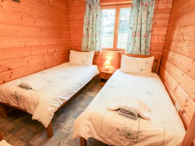 A bedroom with two single beds and a bedside table with a lamp at Chloes Lodge in Middleton Ryedale