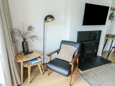 A living room with an armchair and lamp at Bwthyn in Moelfre