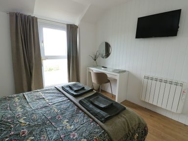 A bedroom with a bed and a desk at Bwthyn in Moelfre