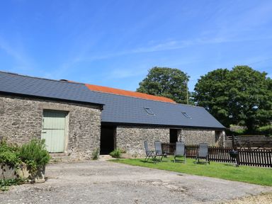 A stone building with a green door and chairs outside at Dale Barton in Wells