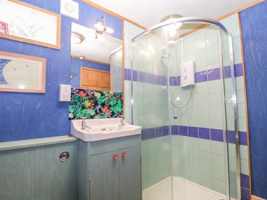 A bathroom with a sink cabinet a shower enclosure and blue walls at Little Willow in Farrington near Child Okeford