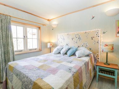A bedroom with a bed covered with a quilt and pillows next to two bedside tables with lamps at Little Willow Farrington near Child Okeford