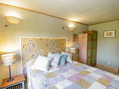 A bedroom with a patchwork quilt on the bed and floral headboard at Little Willow in Farrington near Child Okeford