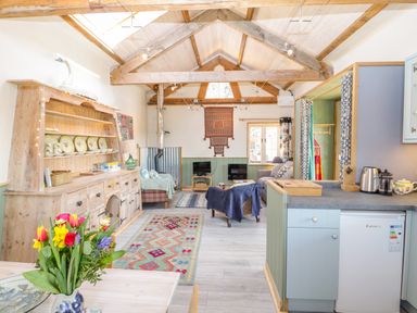 An open plan kitchen and living room with wooden beams and a colorful rug at Little Willow in Farrington near Child Okeford